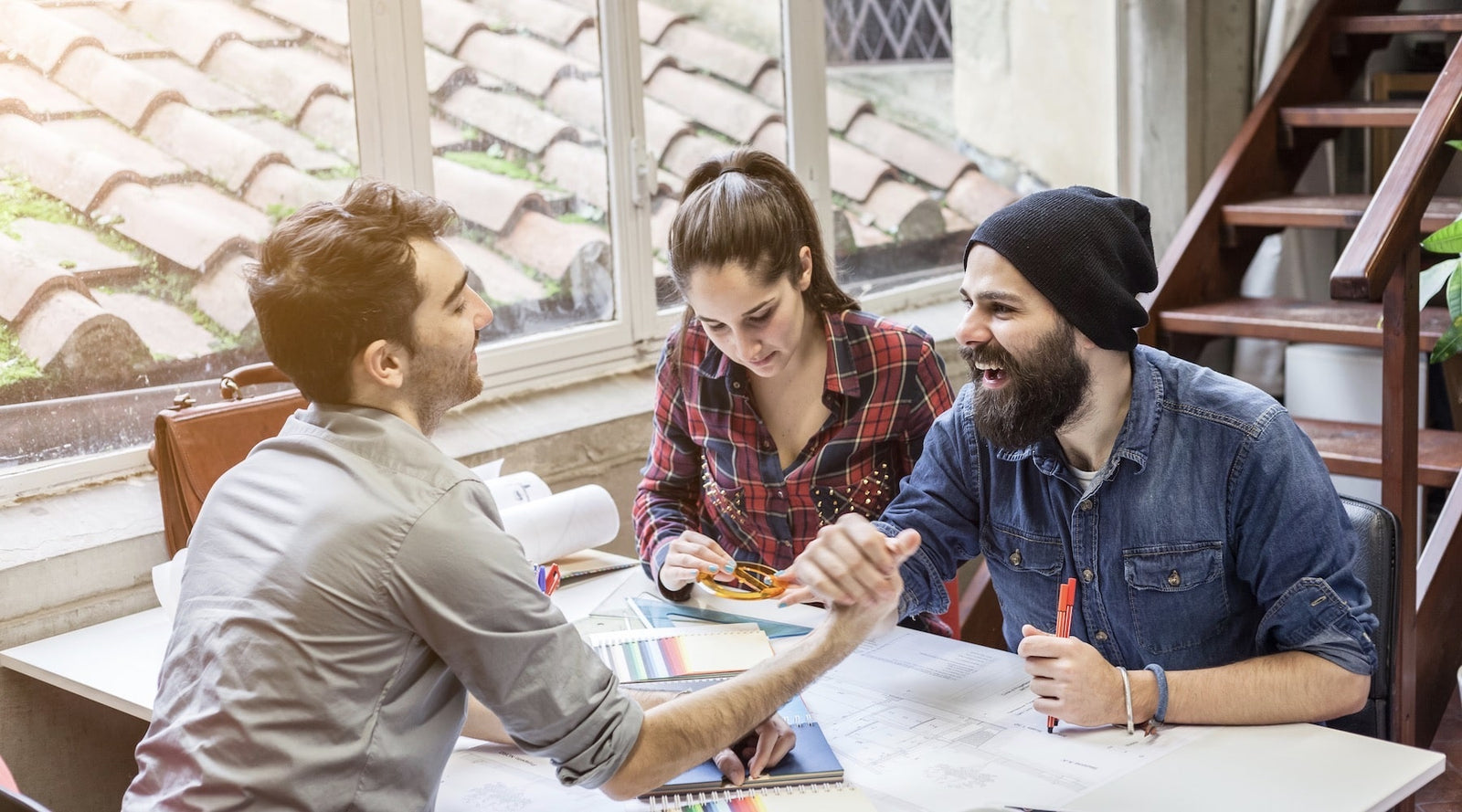 three office workers sitting at a table working