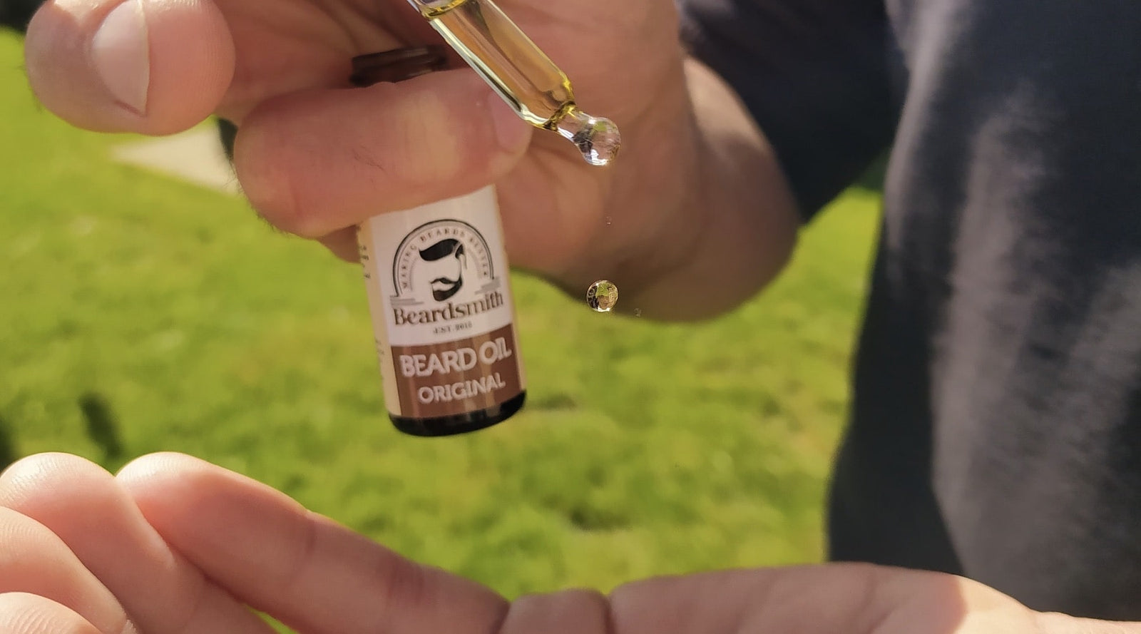 drop of Beardsmith beard oil falling into a hand