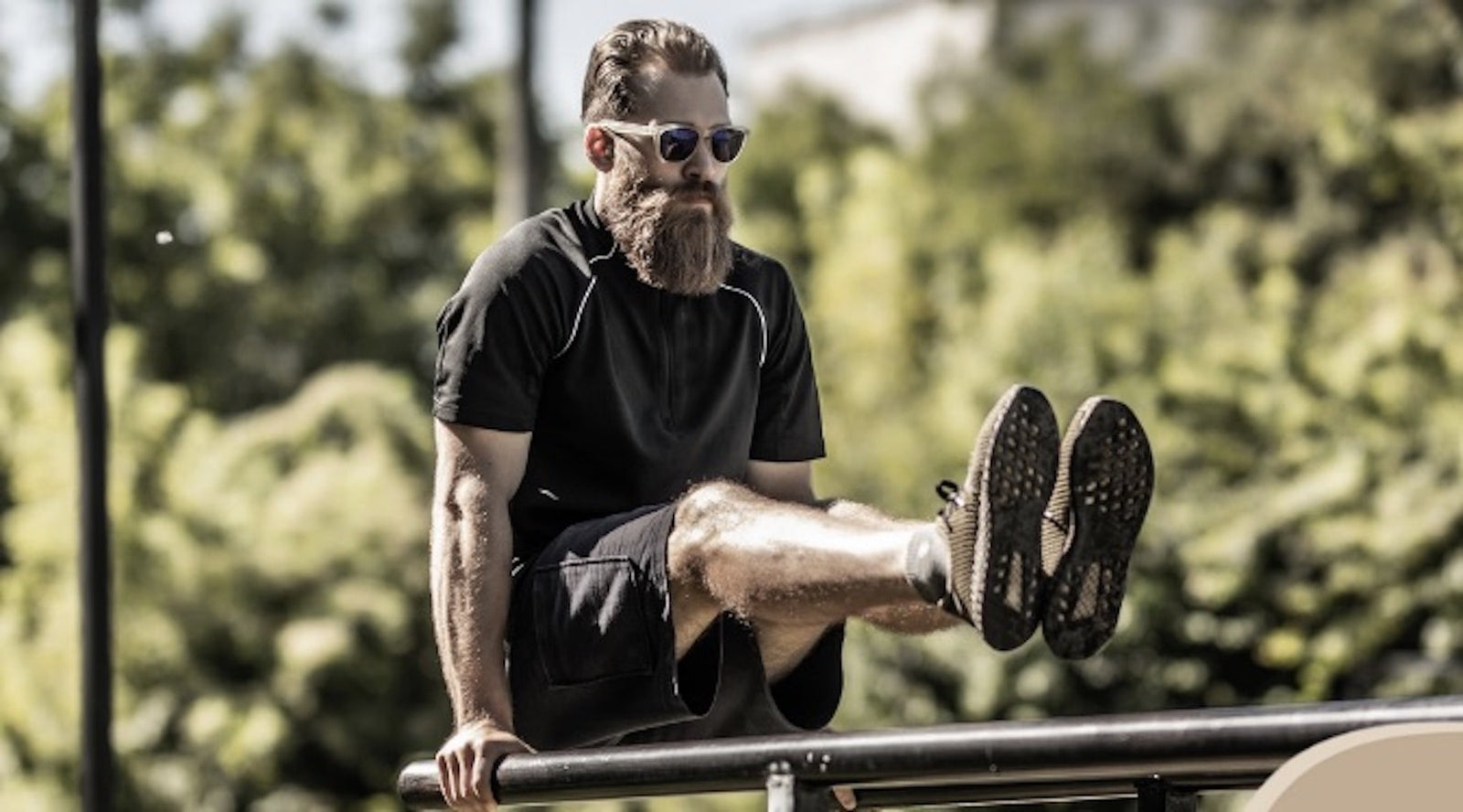 bearded man working out on beams outside