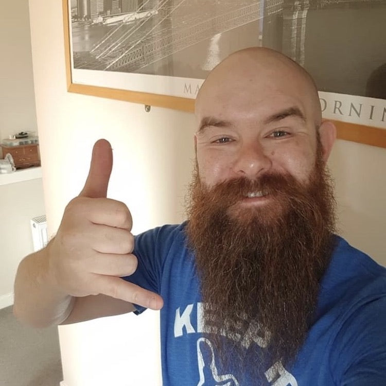 Happy guy with a red beard and a shaved head giving the rock and roll hand sign