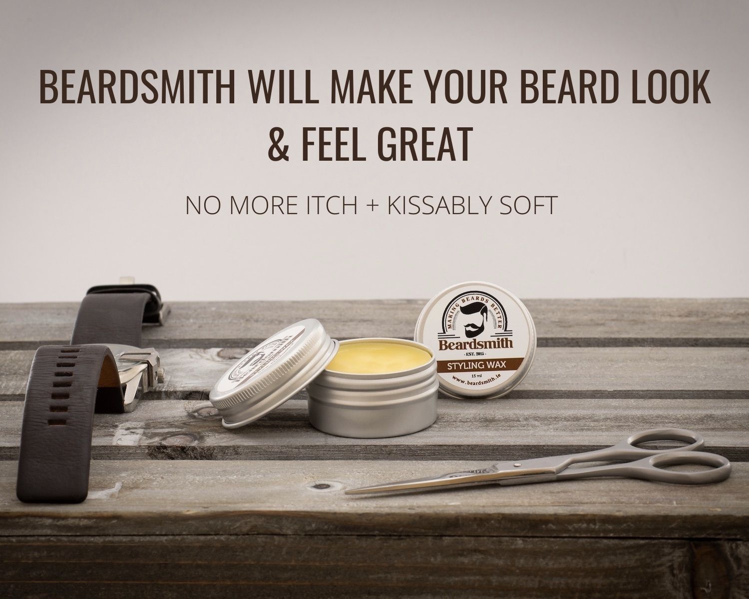 Tin of beard wax on a table with a watch and some scissors