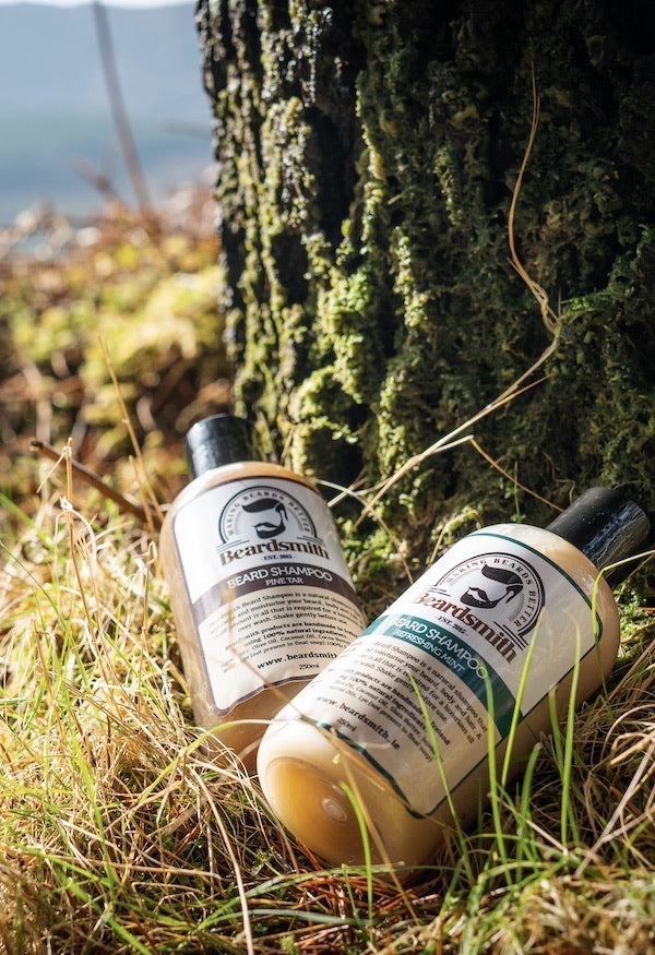 Bottles of Beardsmith beard shampoo lying at the foot of a mossy tree trunk