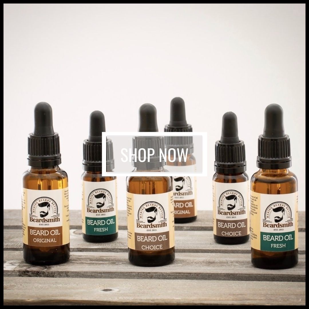 Bottles of Beardsmith beard oil displayed on a wooden bench with a white background